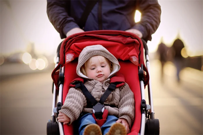 Föräldraledig pappa på promenad med barn i barnvagn